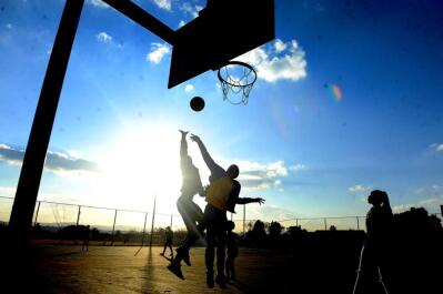School kids playing basketball at sunset