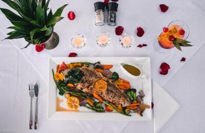 A grilled red snapper fish with roasted vegetables.