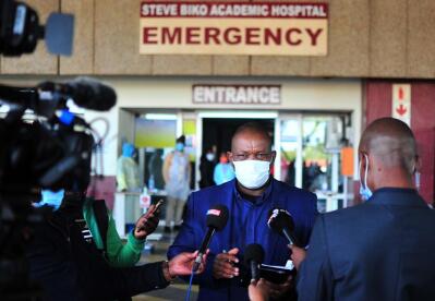 Bust shot of a man speaking to journalists at a hospital