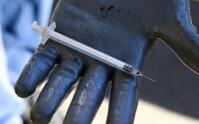 A gloved hand holds a syringe.
