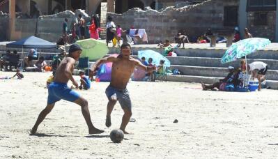 Two men play beach soccer
