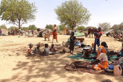 Refugees sit in a shade in Chad.