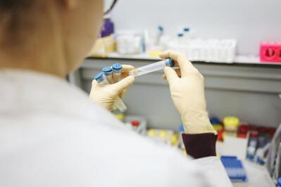 A worker in a lab holds a vacutainer 