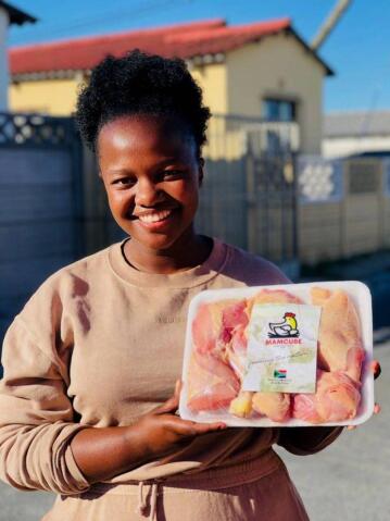 A woman holds up a pack of chicken portions.