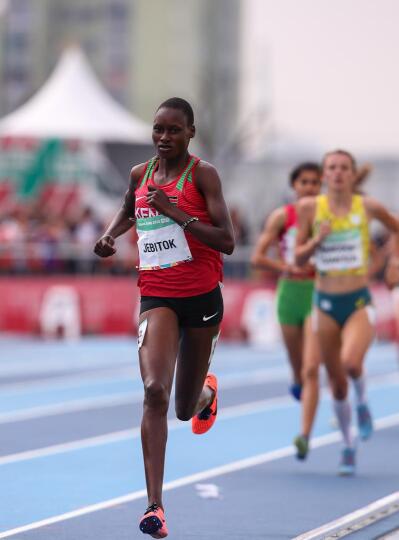 A top Kenyan runner leads a women’s race on a blue tartan athletics track