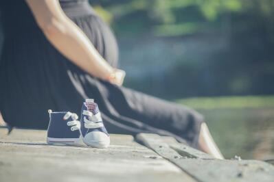 Pregnant woman sitting next to baby shoes