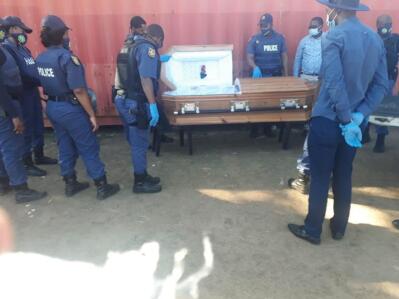 Police officers gather around a stolen coffin to inspect it. 