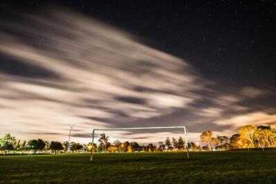 Soccer goalposts with trees in the background lit up at night