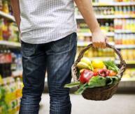 Man carries a shopping basket with fruits and veggies