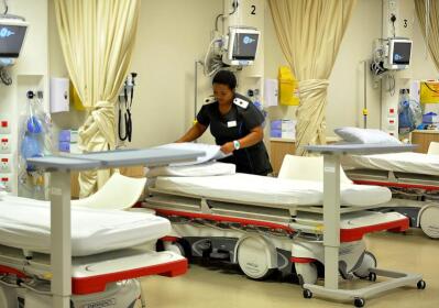 A nurse makes up a bed in a hospital ward.