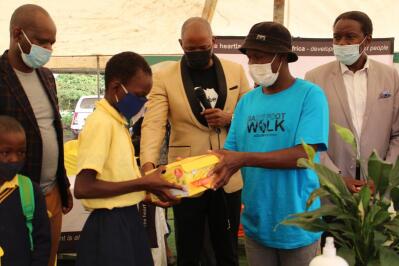 Men handing over school shoes to a learner