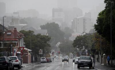 Wet and misty picture of street in Cape Town with cars driving with headlights on. 