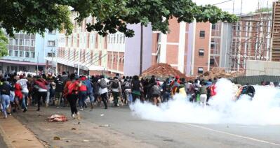 A mob of students flee tear gas in the street.