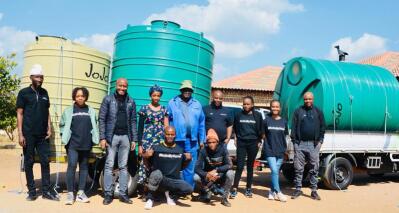 A group of people stand in front of water storage tanks.
