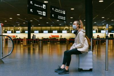 A woman sitting on her luggage at the airport 