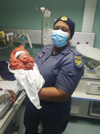 A policewoman holding a newborn baby
