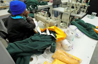 A woman seated at a work station with counterfeit Springbok jerseys.
