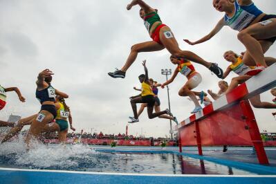 Steeplechase athletes attempt to clear the water hurdle