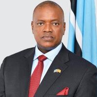 Man in suit in front of Botswana flag.