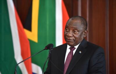 Cyril Ramaphosa speaking into a microphone in front of a South African flag