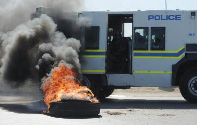 A burning tyre near a police Nyala