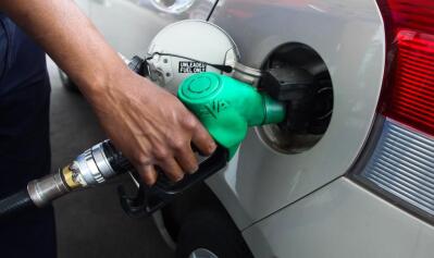The hand of a fuel attendant pouring fuel into a car
