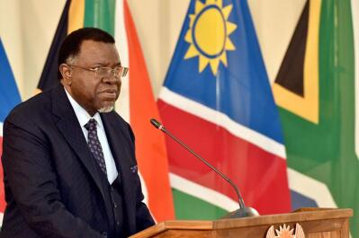 Namibian President Hage Geingob stands in front of a flag.