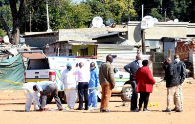 A vehicle parked near a small crowd at an informal settlement