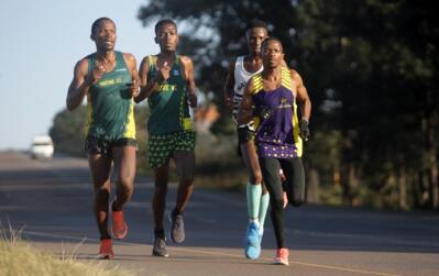 Four athletes running alongside each other on the road