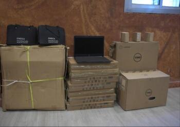 A black laptop sits on top of pile of brown boxes.