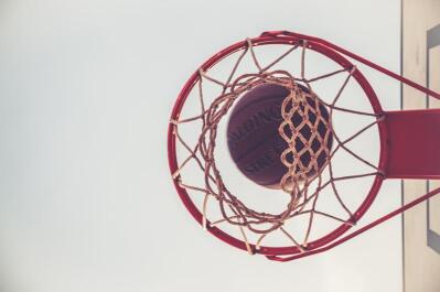 A close-up from the bottom of the basketball hoop as the ball goes through it. 