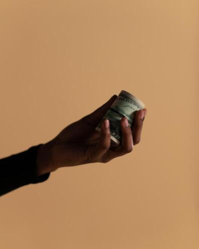 A hand holds a roll of banknotes.