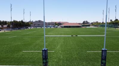 A green rugby field seen from behind the posts