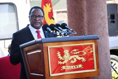 Man speaks at a podium with Malawi coat of arms.
