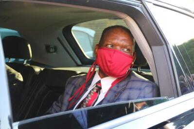 A man wearing a red mask, sitting in the back seat of a car